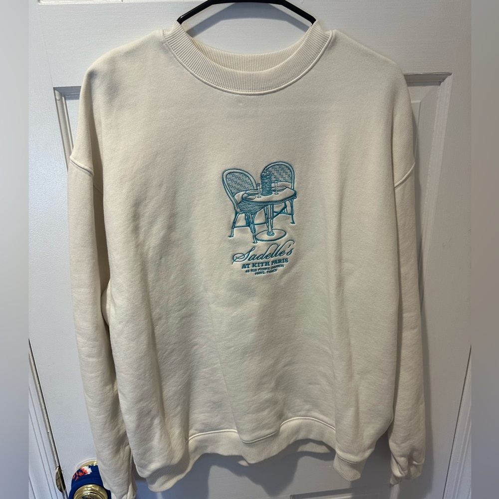 Kith Paris Saddelle’s Cream Crewneck Sweater with Blue Graphic